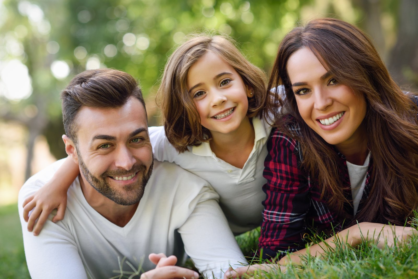 Family enjoying a casual outdoor moment, smiling together on the grass, representing the supportive approach of K Simmons Insurance in helping Sarasota families choose health coverage.